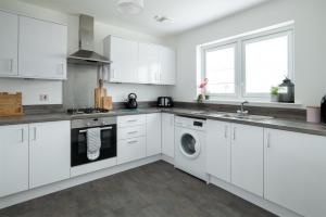 eine Küche mit weißen Schränken, einer Waschmaschine und einem Trockner in der Unterkunft Lily Bank House in Inverness