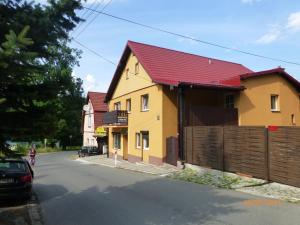 ein Haus mit rotem Dach auf einer Straße in der Unterkunft Pokoje Karkonosze in Preseka