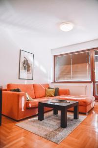 a living room with an orange couch and a table at Apartment Bjelasnica in Bjelašnica