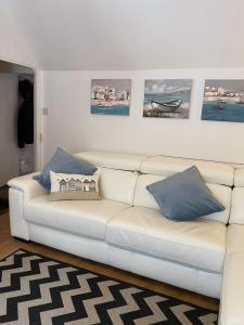 a white couch with blue pillows in a living room at The Nest - St Ives in St Ives