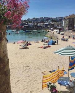 a beach with people laying on the sand and umbrellas at The Nest - St Ives in St Ives