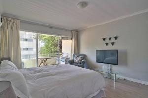 a bedroom with a large bed and a television at Clifton 1st Beach Studio in Cape Town