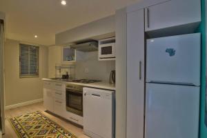 a kitchen with white appliances and a refrigerator at Clifton 1st Beach Studio in Cape Town
