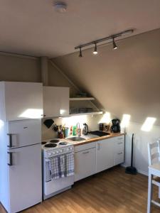 La cuisine est équipée de placards blancs et d'un four avec plaques de cuisson. dans l'établissement Tufte Gård, à Ulefoss