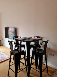 une table noire et quatre chaises dans une pièce dans l'établissement Emerald Blossom-Central Warrington, Luxurious Yet Homely, WiFi, Secure Parking, à Warrington