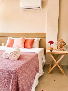 um quarto com uma cama com almofadas vermelhas e uma mesa em Pousada Praiana em Porto de Galinhas