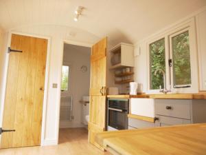 cocina con armarios blancos y encimera de madera en Wolstonbury Getaway en Hassocks