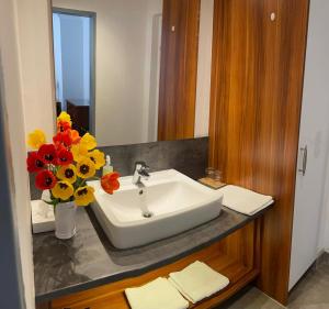 a bathroom sink with a vase of flowers on a counter at Landgasthof zur Post in Mitterdorf im Mürztal