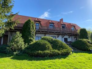a large house with a balcony on top of a yard at Mazurska Zagroda in Rydzewo