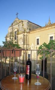 una bottiglia di vino seduta su un tavolo con due bicchieri di Gualtiero Camere & Suite a Caltagirone