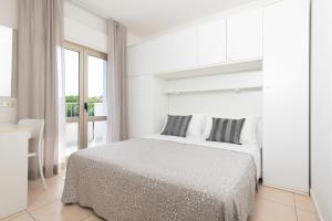 una camera da letto bianca con un letto e una finestra di Residence Quadrifoglio a Cervia Altre 36 foto