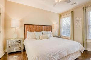a bedroom with a large white bed and two windows at Price Street Place in Savannah