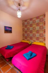 two beds in a room with red sheets at tuGuest Aljibe del Rey Apartment - Free parking in Granada