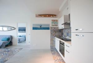 una cocina con armarios blancos y una cama en una habitación en Surf and Windsurfer House Anzio, en Anzio