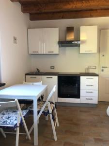 eine Küche mit weißen Schränken sowie einem Tisch und Stühlen in der Unterkunft Barcola mare apartment in Triest