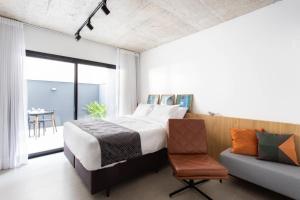 a bedroom with a bed and a chair and a table at Charlie Porto Alegre Praça 4 in Porto Alegre