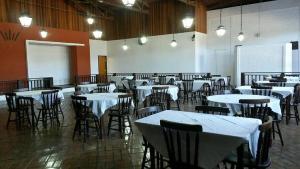 a dining room with tables and chairs with white tables at Hotel Tropeiro da Lapa in Lapa