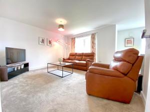 エルギンにある100 Thornhill Drive, Elginのリビングルーム(革張りの椅子2脚、テレビ付)