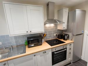 een keuken met witte kasten, een wastafel en een magnetron bij Catref in Llangollen