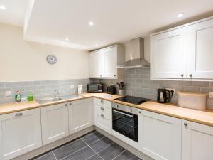 a kitchen with white cabinets and a stove top oven at Hafan in Llangollen