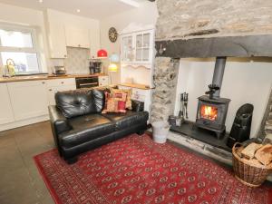 a living room with a leather couch and a fireplace at Bwthyn Afon River Cottage in Blaenau-Ffestiniog