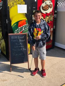 a young boy is standing next to a sign at Gold Crest Motel in Wildwood Crest