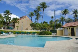 a large swimming pool with chairs and palm trees at Simple Hollywood Beach in Humacao