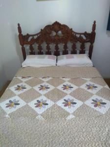 a bed with a wooden head board with flowers on it at Pousada Várzea da Serra in Jaboticatubas