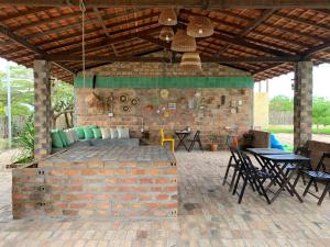 un patio con una pared de ladrillo, mesas y sillas en Quintal de Areias en Santo Amaro