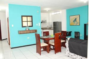 cocina con mesa, sillas y pared azul en Departamentos de 2 y 3 Habitaciones en el Centro de MANTA en Manta