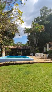 una piscina con mesas blancas y sillas en un parque en Chacara bica dágua, en Pirenópolis