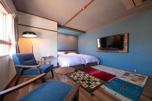 um quarto com uma cama e uma cadeira e uma televisão em Kunisakisou em Beppu