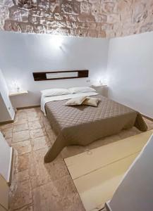 - une chambre avec un lit et un mur en pierre dans l'établissement Trulli Belvedere di Puglia, à Selva di Fasano