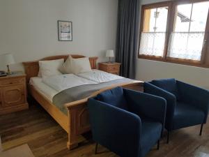 a bedroom with a bed and two blue chairs at Hotel Beau-Séjour in Leukerbad