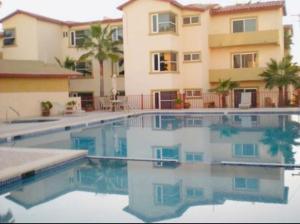 a large swimming pool in front of a building at Sol-O-Cien Condo No Check Out Chores in Rosarito