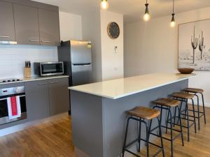 a kitchen with a counter and bar stools in it at Captains Cove Ground Floor Luxury Apartments - Free Netflix in Paynesville