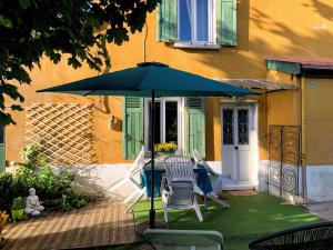 a table and chairs under an umbrella in front of a house at "La petite Maison" in Sainte-Foy-lès-Lyon
