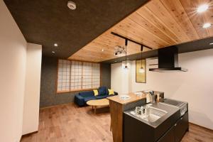 a kitchen and living room with a blue couch at Manabi-stay Takayama SAKURA 提携駐車場利用可 古い町並みまで徒歩1分 最大9名宿泊可能な一等地で人工温泉を楽しむ in Takayama