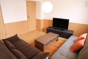 uma sala de estar com um sofá e uma televisão de ecrã plano em ケイアイコンホテルズ 新栄301 em Aoichō