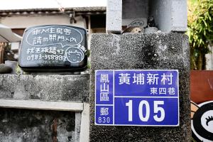 un panneau de rue et un panneau sur un mur dans l'établissement Here Sleep Guesthouse, à Kaohsiung