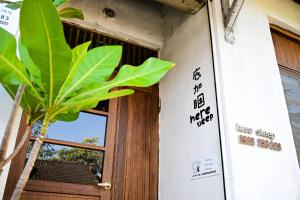 una puerta con un cartel junto a una planta en Here Sleep Guesthouse, en Kaohsiung