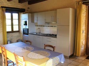 een keuken met een tafel en een witte koelkast bij Gîte Salignac-Eyvigues, 4 pièces, 6 personnes - FR-1-616-88 in Salignac Eyvigues