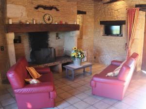een woonkamer met 2 rode stoelen en een open haard bij Gîte Salignac-Eyvigues, 4 pièces, 6 personnes - FR-1-616-88 in Salignac Eyvigues