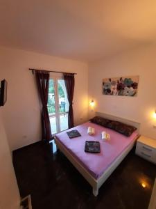 a bedroom with a bed with purple sheets and a window at Apartments Pitarević in Saplunara