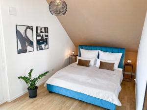 a bedroom with a blue bed and a potted plant at Modern & Stylisch: Maisonette Wohnung in Freising in Freising