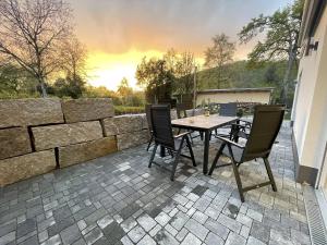 un patio avec une table et des chaises et un mur en pierre dans l'établissement Ferienwohnung am Park, à Badenweiler