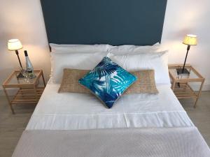 a bed with white sheets and a blue pillow on it at Océano Home in Ayamonte