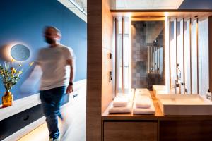 a man is walking in a bathroom with a sink at KONCEPT HOTEL Josefine in Cologne