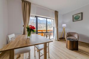 uma sala de estar com uma mesa com um vaso de flores em Yael Luxury Apartments 4 em Buşteni