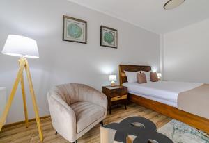 ein Schlafzimmer mit einem Bett, einem Stuhl und einer Lampe in der Unterkunft Yael Luxury Apartments 4 in Buşteni